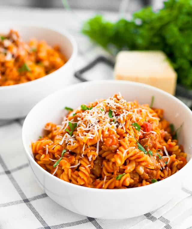 instant pot pasta with meat sauce in a white bowl topped with shredded cheese