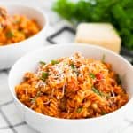 instant pot pasta with meat sauce in a white bowl topped with shredded cheese