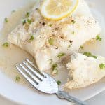 air fryer frozen fish fillets with a fork and lemon slice on a white plate