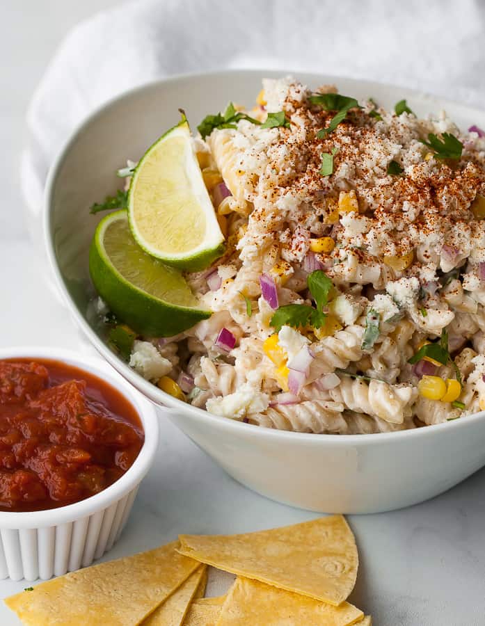 Mexican Street Corn Pasta Salad in a white dish next to a small white dish of salsa