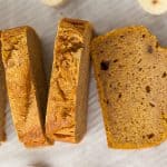 pumpkin banana bread sliced on a pan with bananas