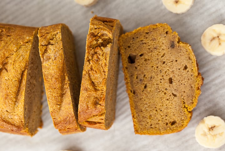 pumpkin banana bread sliced on a pan with bananas