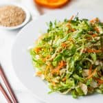 shaved brussels sprouts on a white plate with chopsticks