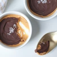 two keto peanut butter cup with sea salt in white dishes alongside a spoonful
