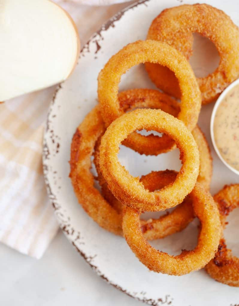 onion rings and dipping sauce on a white plate