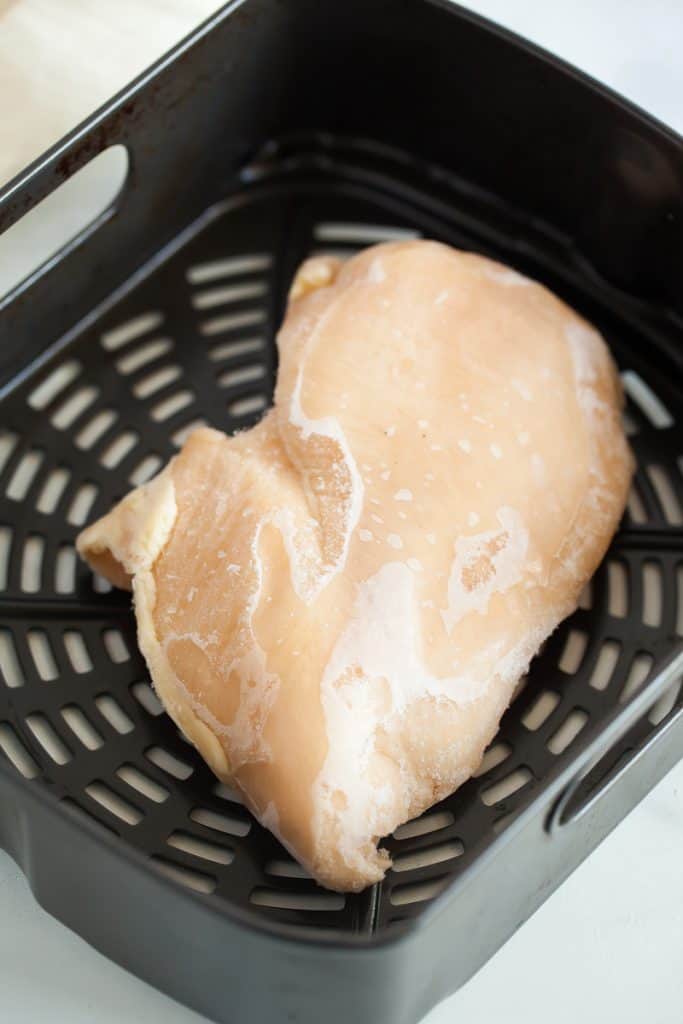 raw chicken breast in air fryer basket
