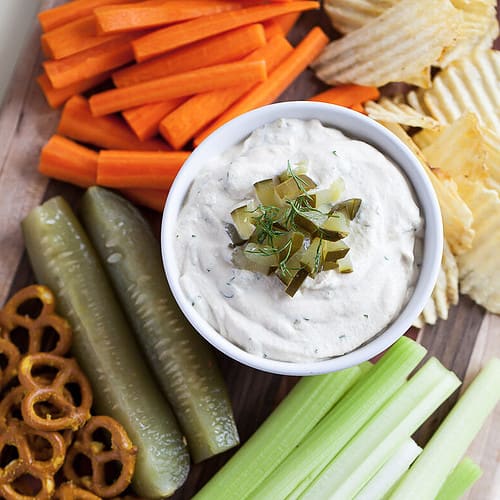 Vegan Dill Pickle Dip surrounded by vegetables and pretzels for dipping