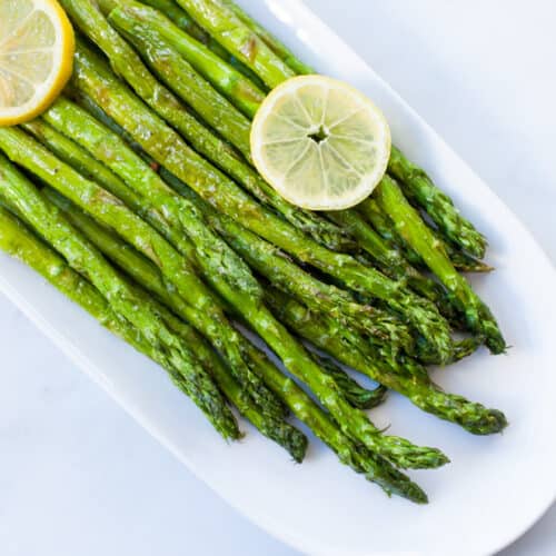 air fryer frozen asparagus and lemon slices on a white plate