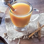 a cup of hot apple cider in a mug with a cinnamon stick