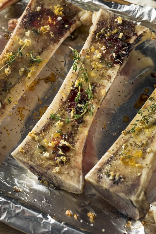 bone marrow on foil that is roasted and topped with herbs