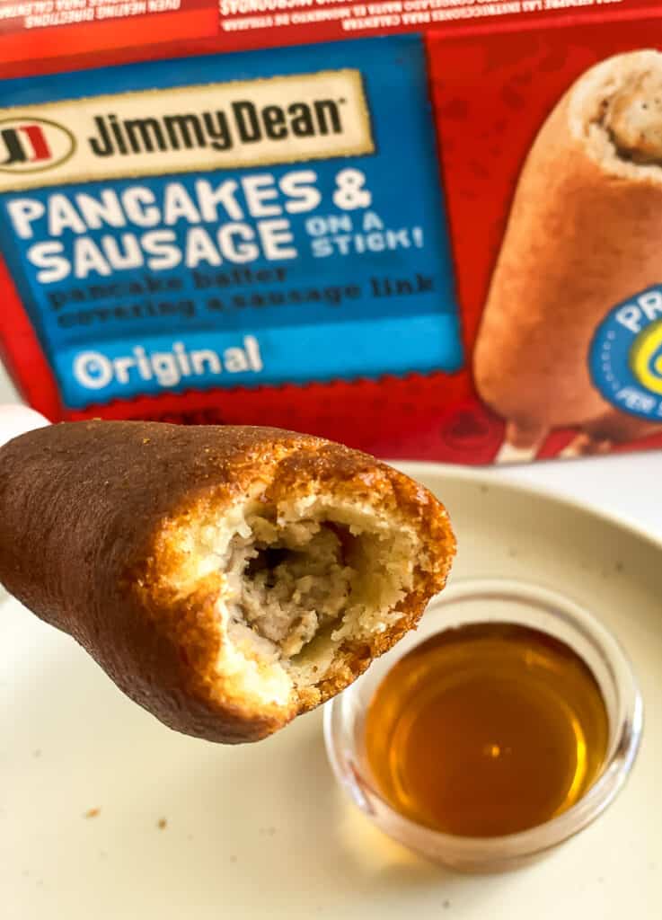 close up of a cooked jimmy dean pancakes and sausage on a stick with syrup. 