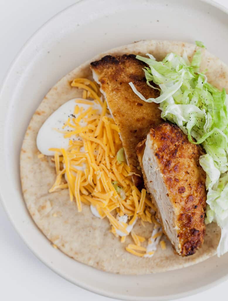 chicken tender with lettuce, cheese, and ranch dressing on a tortilla