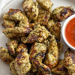 bite sized pieces of pesto chicken on a plate with marinara sauce
