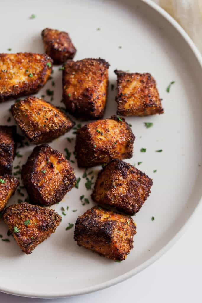 pieces of blackened salmon on a plate sprinkled with parsley