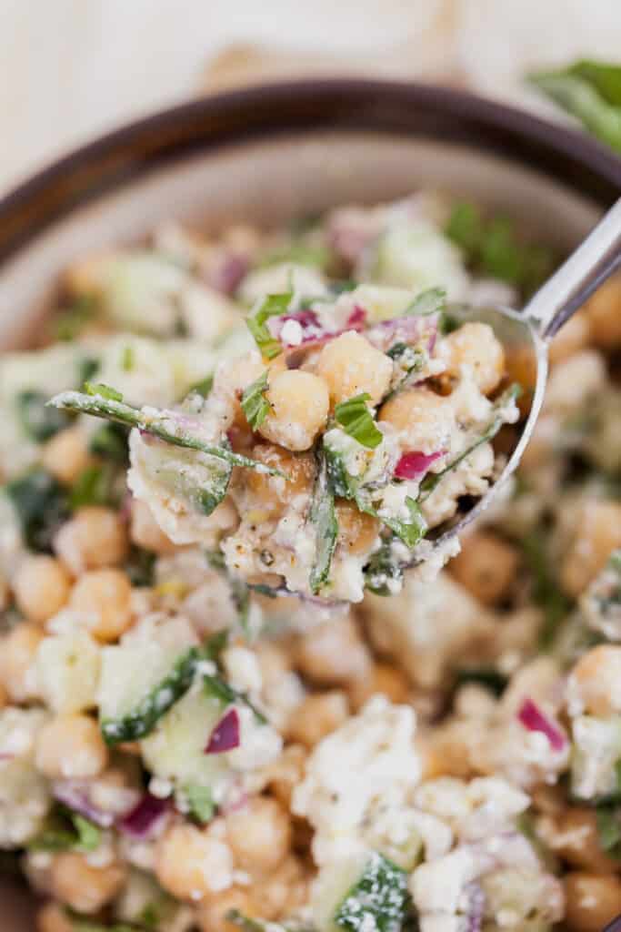 spoonful of salad in a bowl with chickpeas, cucumbers, and feta cheese