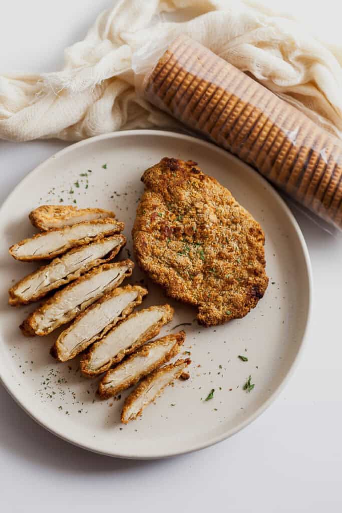 chicken breast coated in cracker breadcrumbs and sliced on a plate