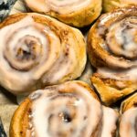 cinnamon rolls with frosting on a parchment paper liner