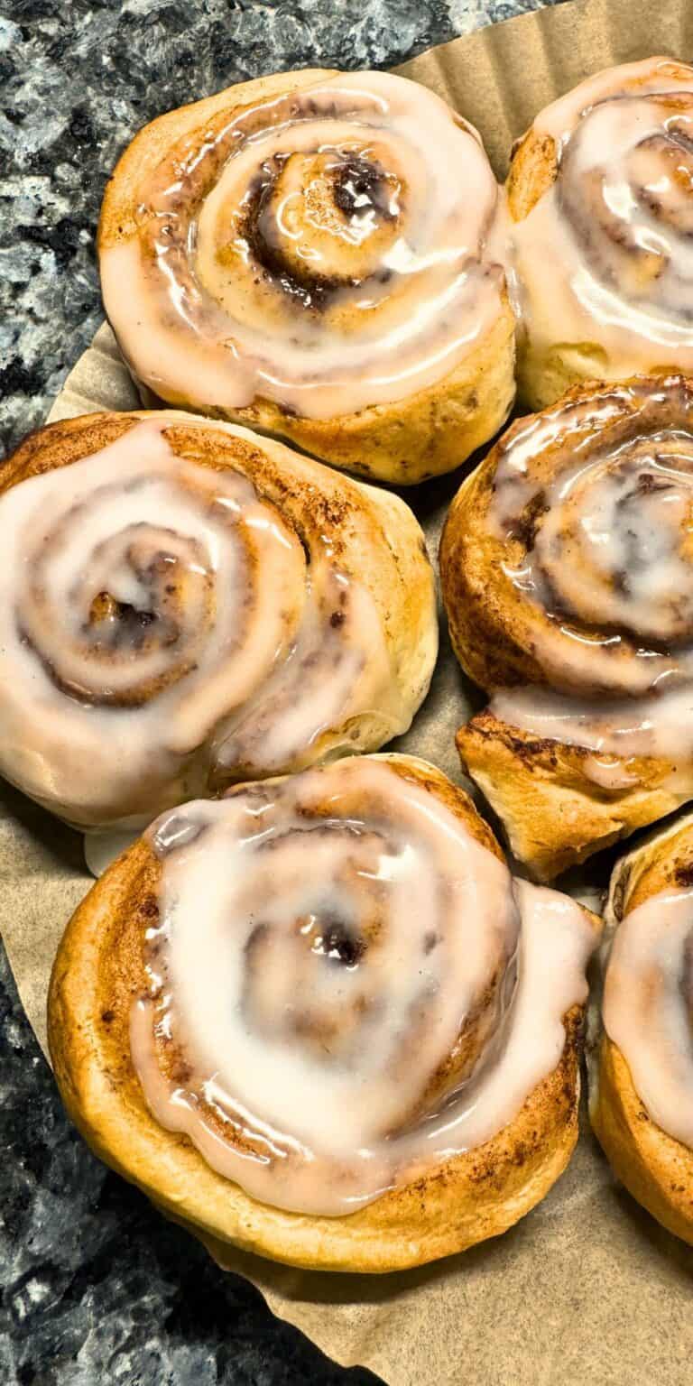 cinnamon rolls with frosting on a parchment paper liner