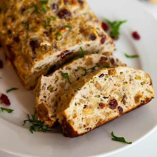 chicken meatloaf sliced on a plate with cranberries and stuffing