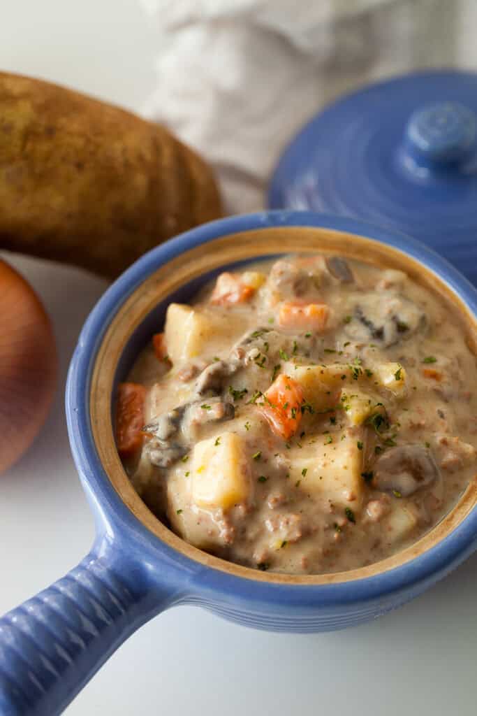 potato and hamburger soup in a blue crock