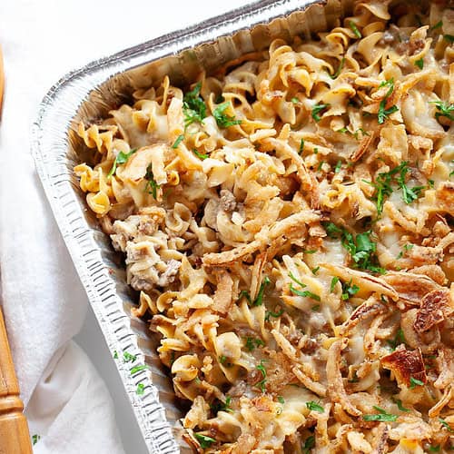 a casserole tray of pasta bake with ground beef, onions, and a creamy sauce