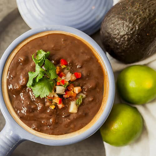 black bean soup in a small blue crock with pico de gallo on top