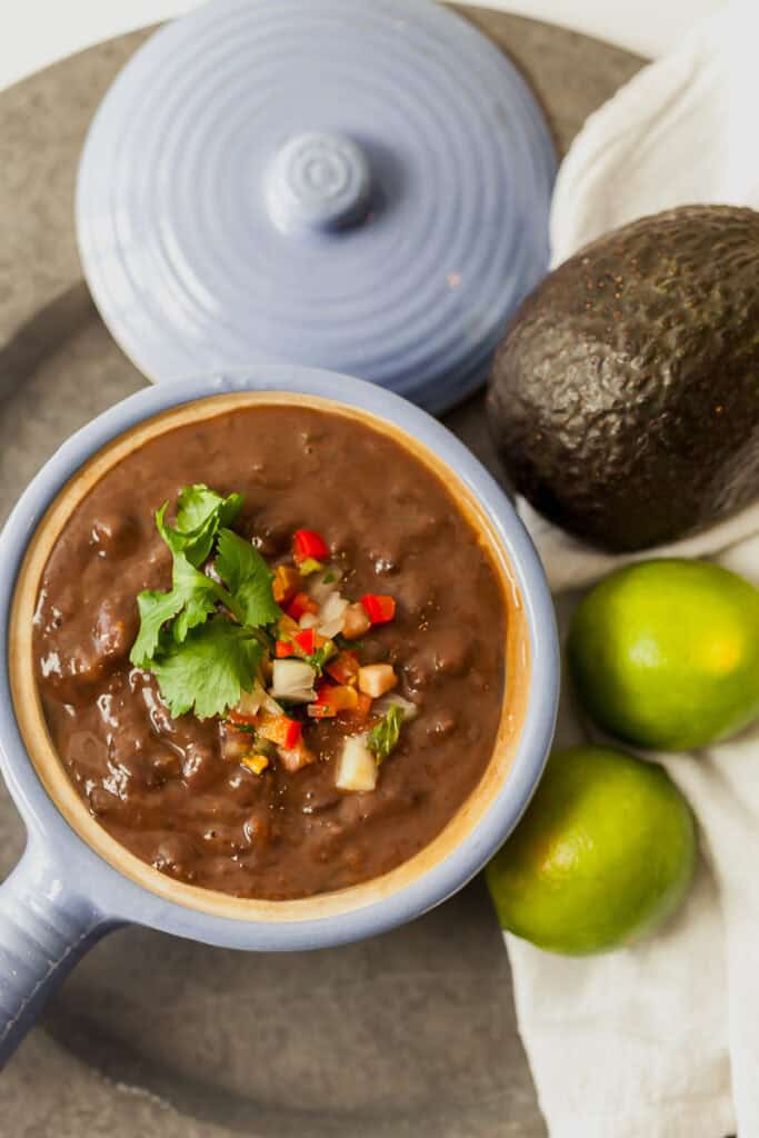 black bean soup in a small blue crock with pico de gallo on top