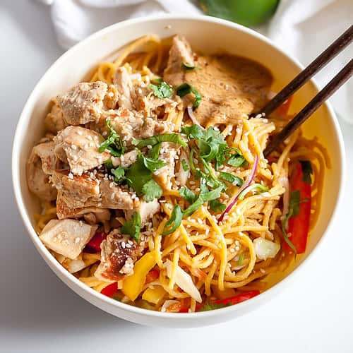 chicken with sesame peanut noodles in a bowl with chopsticks