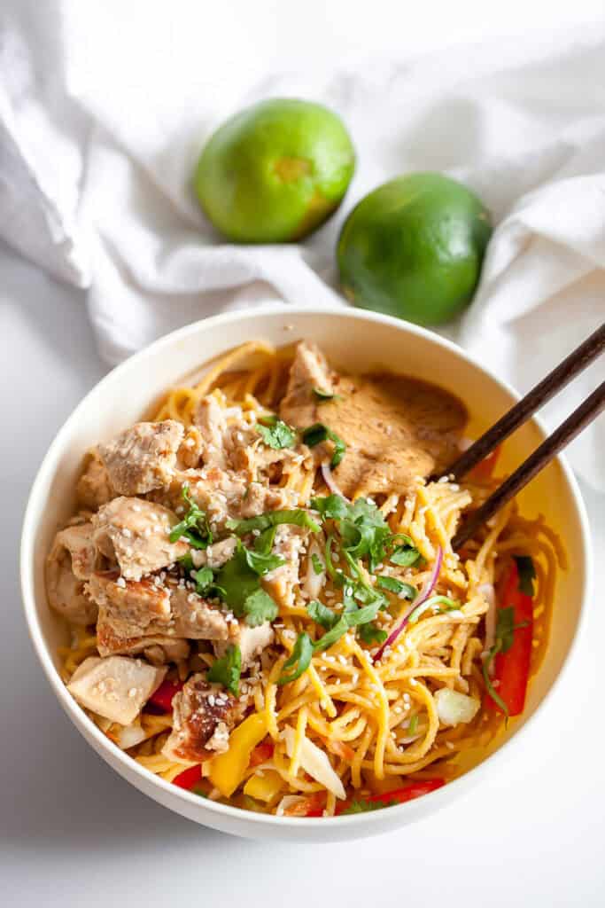 chicken with sesame peanut noodles in a bowl with chopsticks