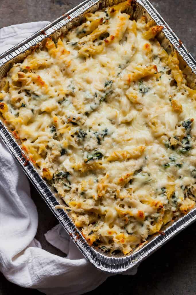 baked pasta with spinach and cheese in an aluminum tray