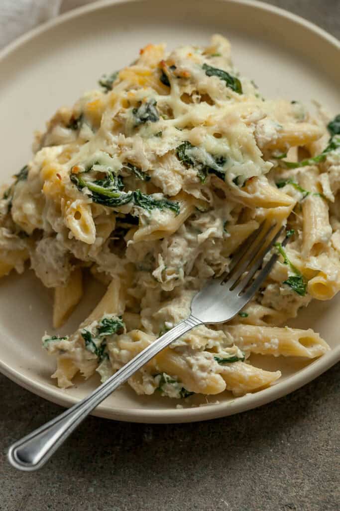 creamy spinach chicken pasta on a plate with a fork
